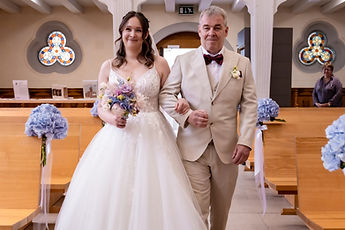 Lucie smiles as she walks up the aisle on a loved one's arm