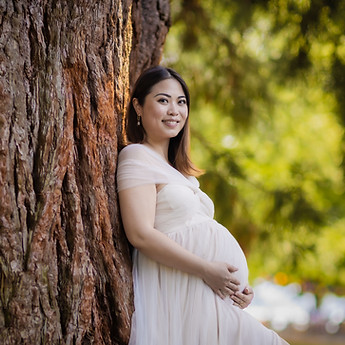 Smiling mother-to-be against a tree trunk