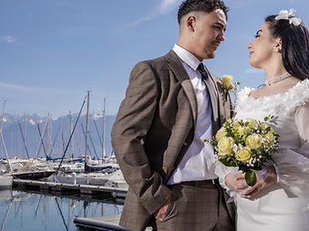 Naz and Ismail, newlyweds by a marina with mountains in the background