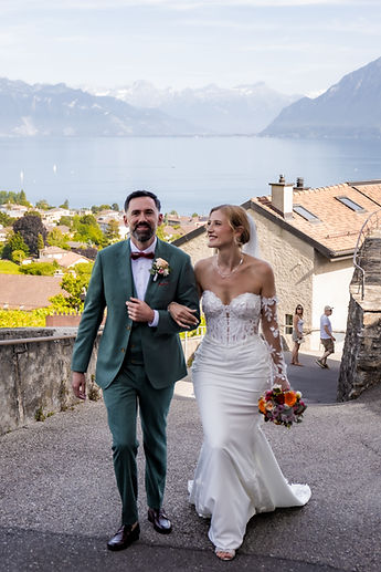 The couple walking together, with the village and the lake below