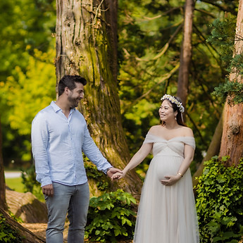 Parents-to-be hand in hand among the tall trees