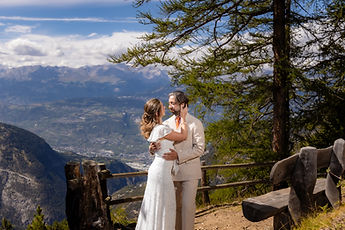 The couple embracing by a wooden fence, the valley far below