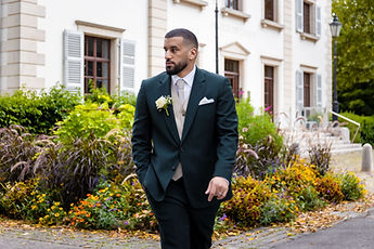 Marouan, one hand in his pocket, in front of the flowers