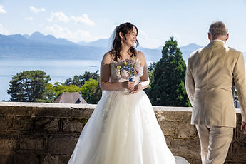 Lucie looks at her bouquet, the lake behind her