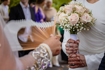 Detail: the wooden fan, the rose bouquet and hennaed hands