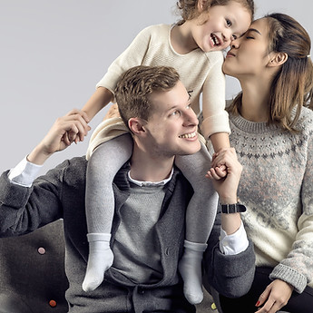 Little girl on her dad's shoulders, kissing her mum