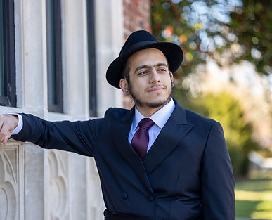 newly wed groom leaning against a beautfiul brick building posing for his wedding photoshoot