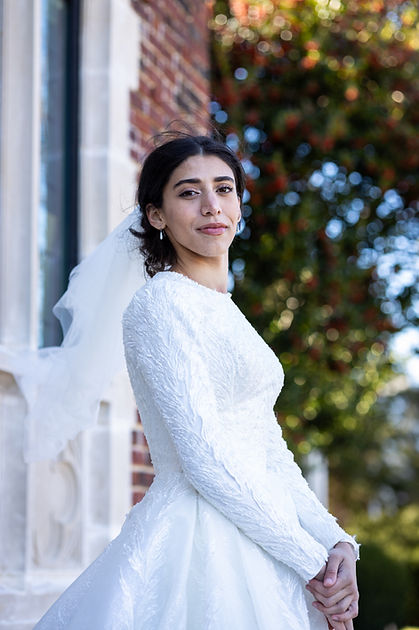 newly married bride leaning against a beautiful brick building posing her her wedding photoshoot