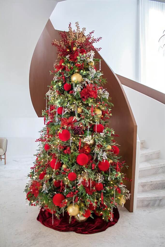 Luxury red and gold Christmas tree decoration styled in a contemporary Sydney home interior with festive ornaments and greenery.