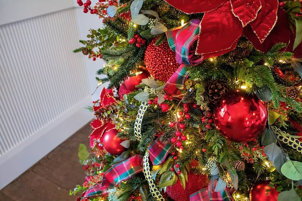 Festive Christmas tree adorned with red ornaments, plaid ribbons, and lights. Greenery and berries enhance the holiday spirit.