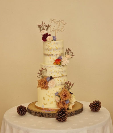 Cream cake with fresh flowers and gold leaf