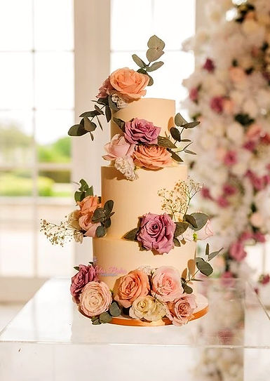 3 tier wedding cake in cream decorated with colourful flowers