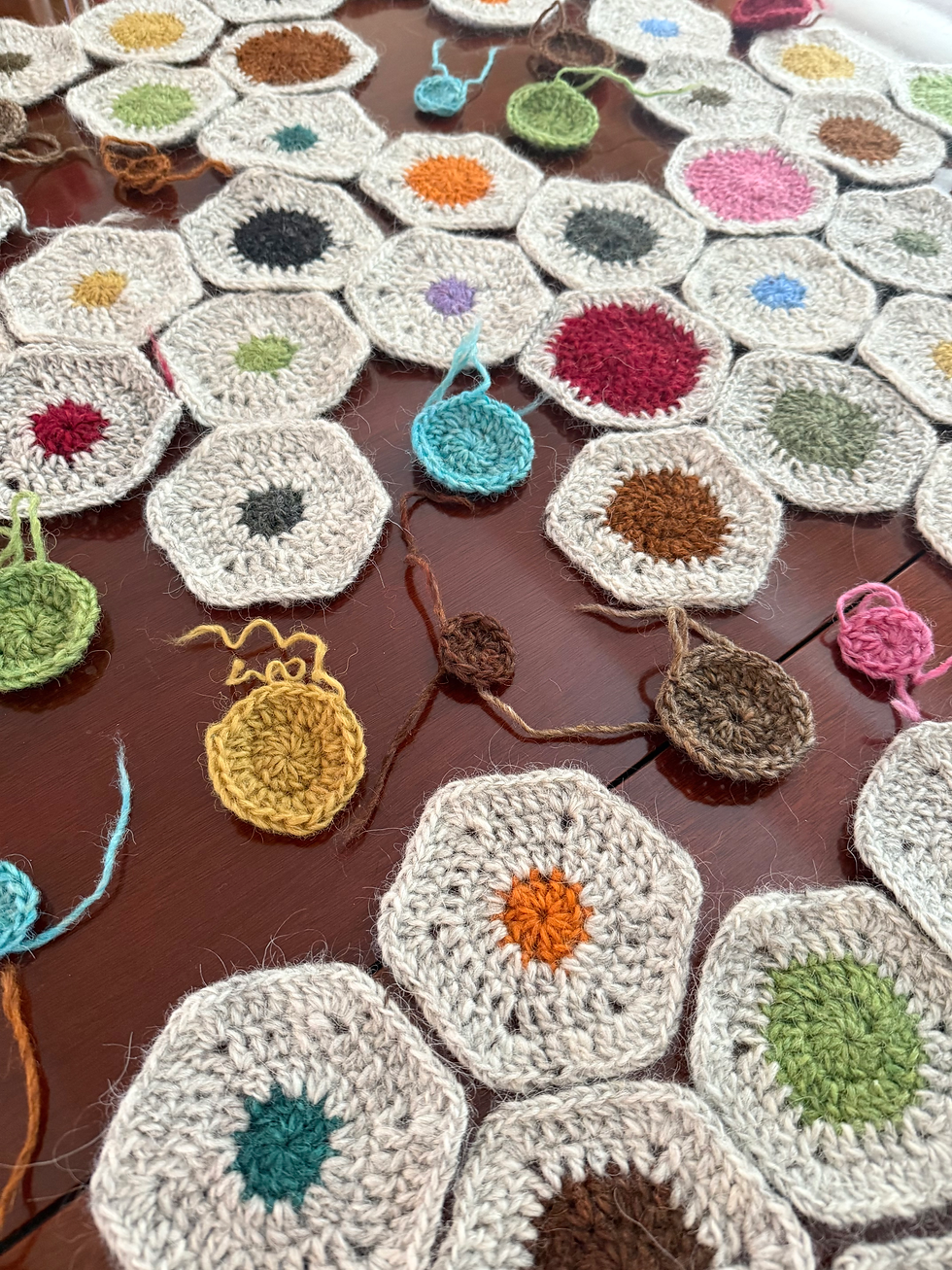 Crochet hexagons in color laying on a brown table as a work in progress lap blanket