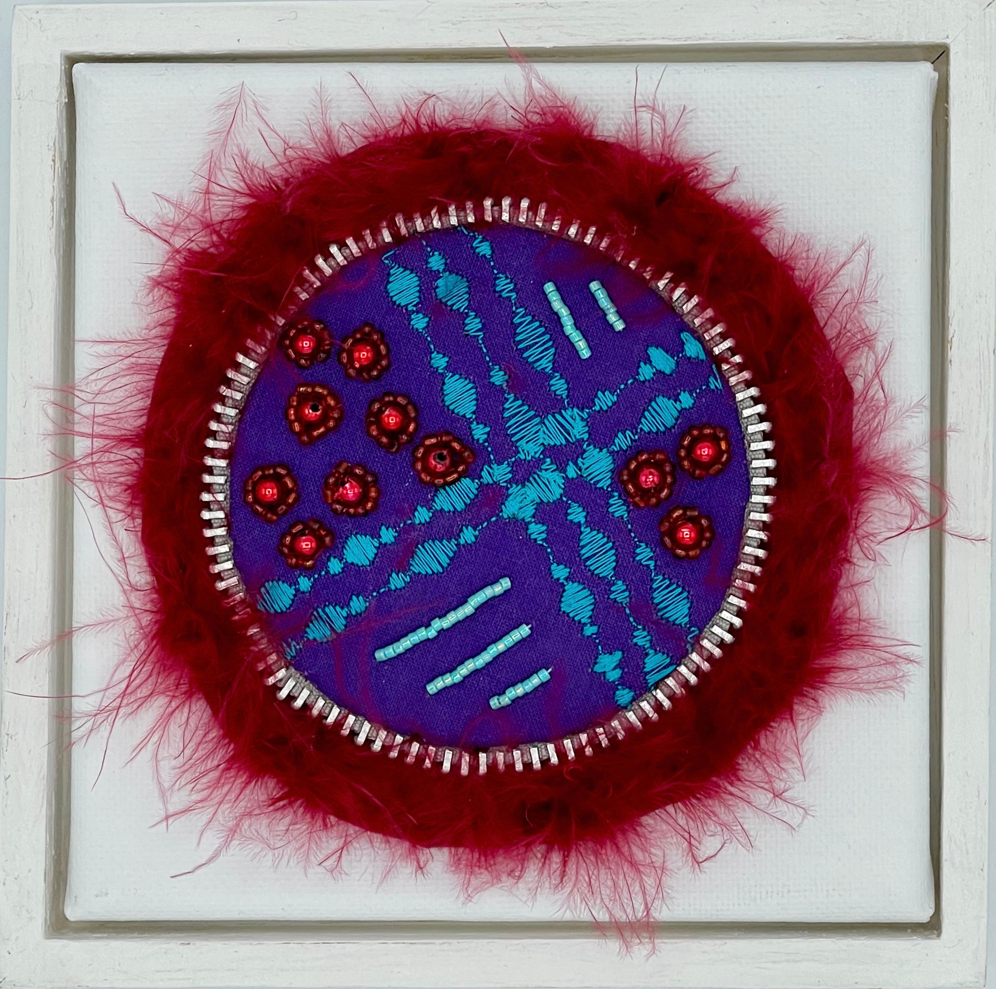 Embroidered circular artwork with red feathers