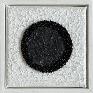 Black circle bead art on white textured canvas