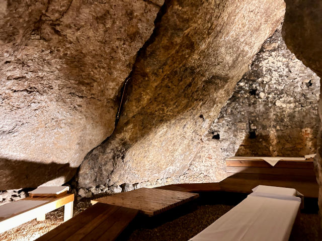 Höhle mit gigantischen Felsblöcken und Ruheliegen mit Saunatüchern