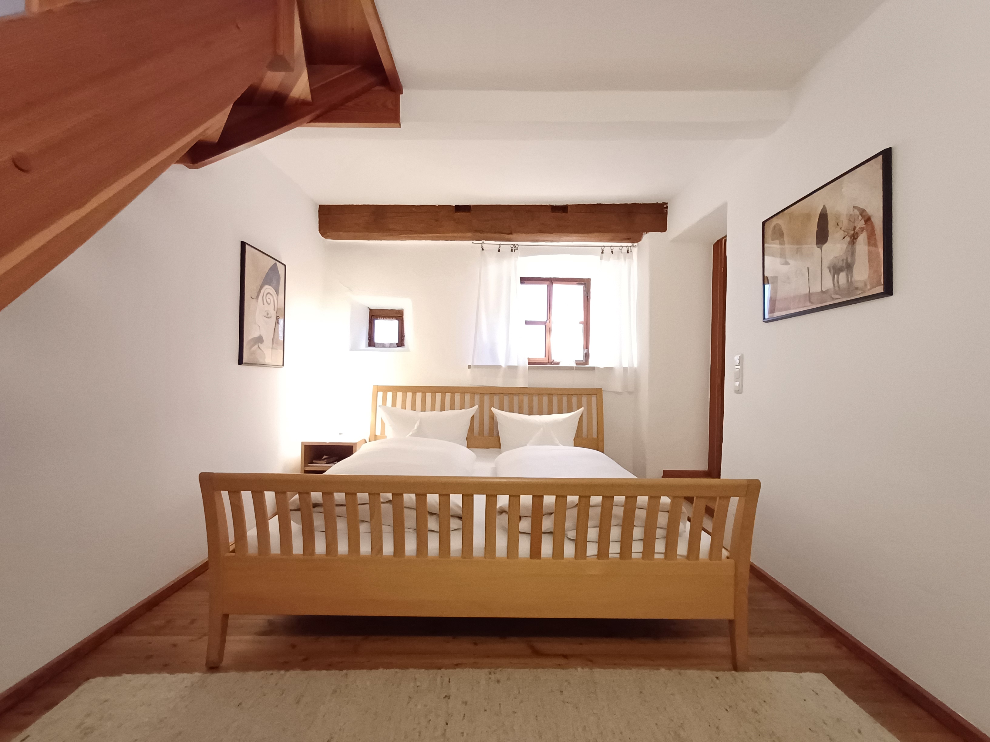 Doppelbett in historischem Raum mit kleinen Fenstern und Wohlfühlatmosphäre