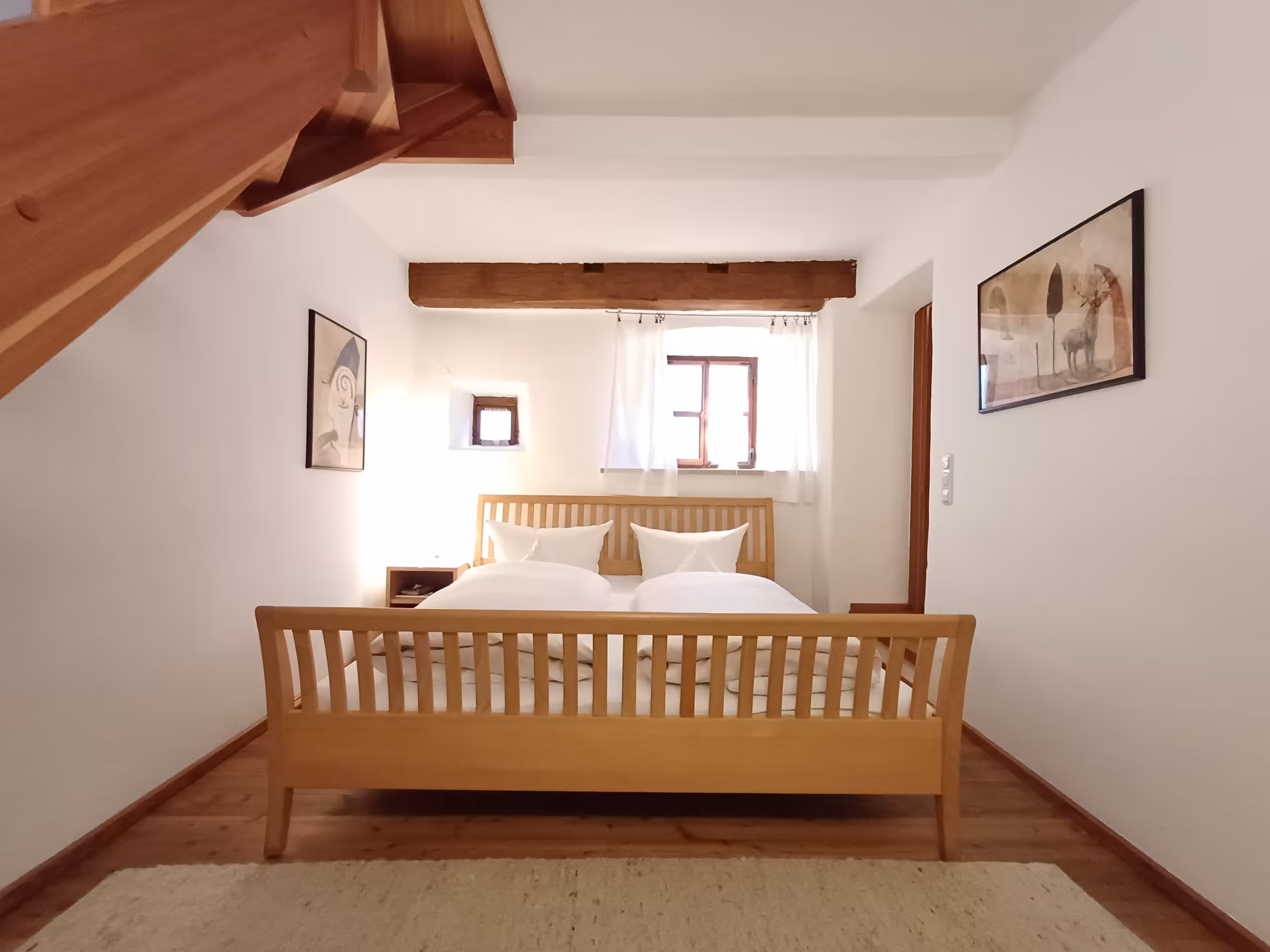 Doppelbett in historischem Raum mit kleinen Fenstern und Wohlfühlatmosphäre