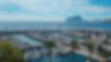 A picture of the marina in Moraira, Alicante, Spain showing powerboats, sailboats and yachts surrounded by the blue waters of the Mediterrean Sea