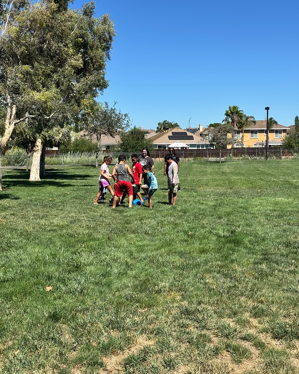 A group of people standing in a circle on a grassy field.