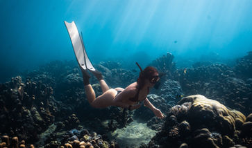 A female freediver explores the beautiful underwater reefs of Amed Bali
