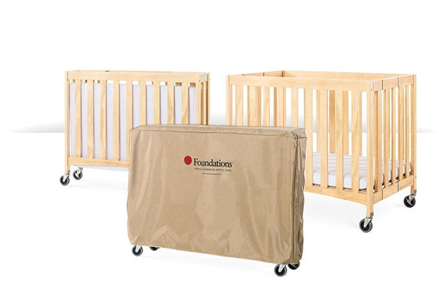 Portable travel sleeper crib in a natural wood finish with slatted sides and compact design, ideal for on-the-go use.