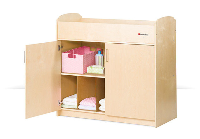 Wooden storage unit with open shelves and two pink fabric bins, designed for children's rooms.