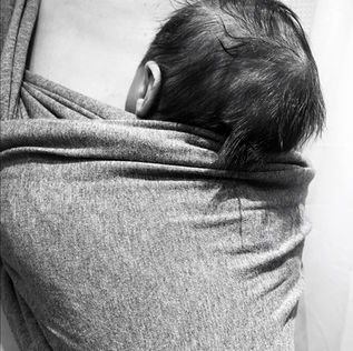 Bébé porté en écharpe dans les bras de son parent
