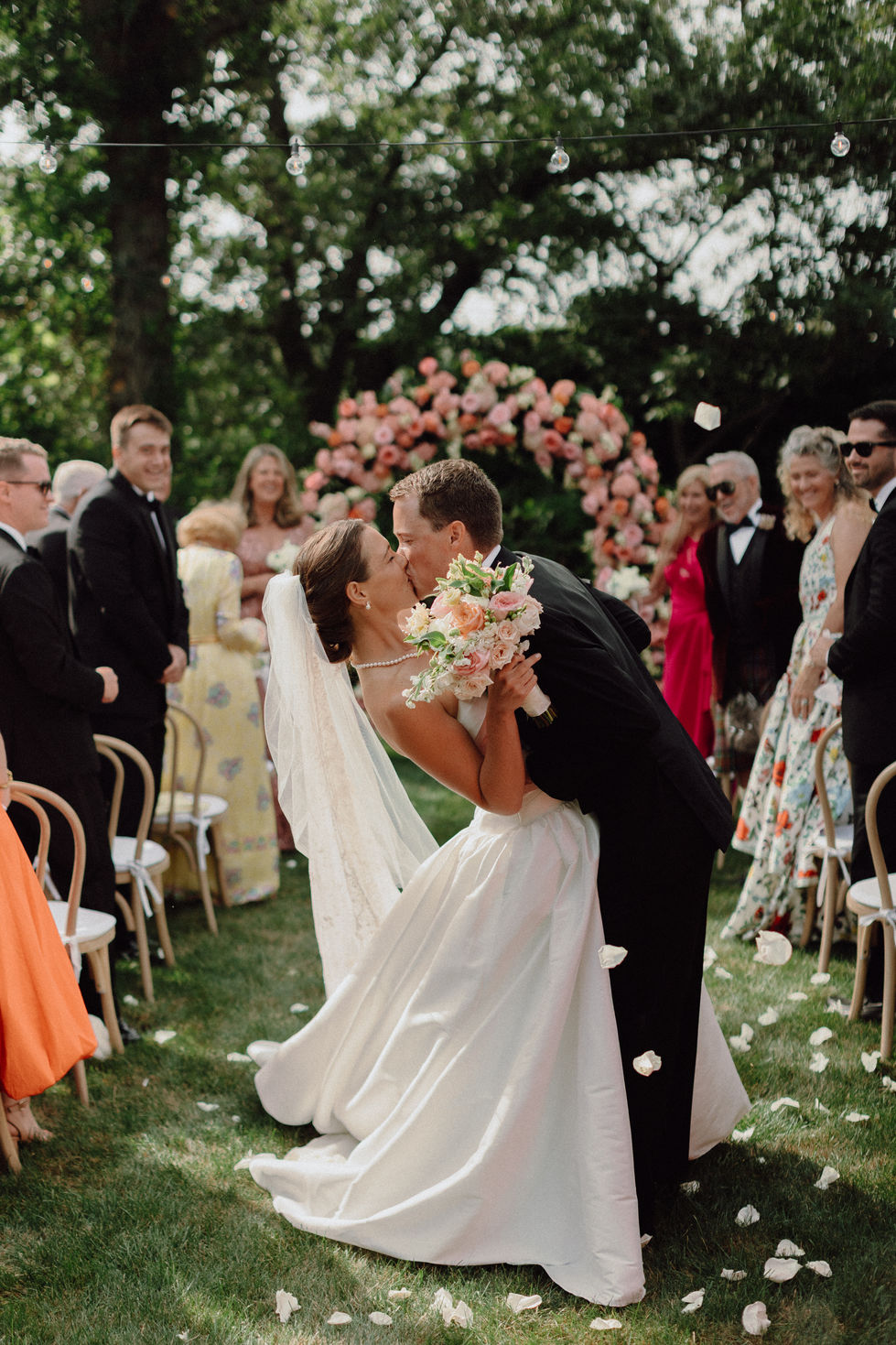 Bride and groom kissing at outdoor wedding ceremony.
