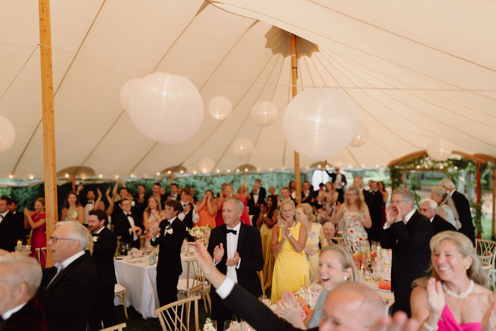 People celebrating under a decorated tent at an event.