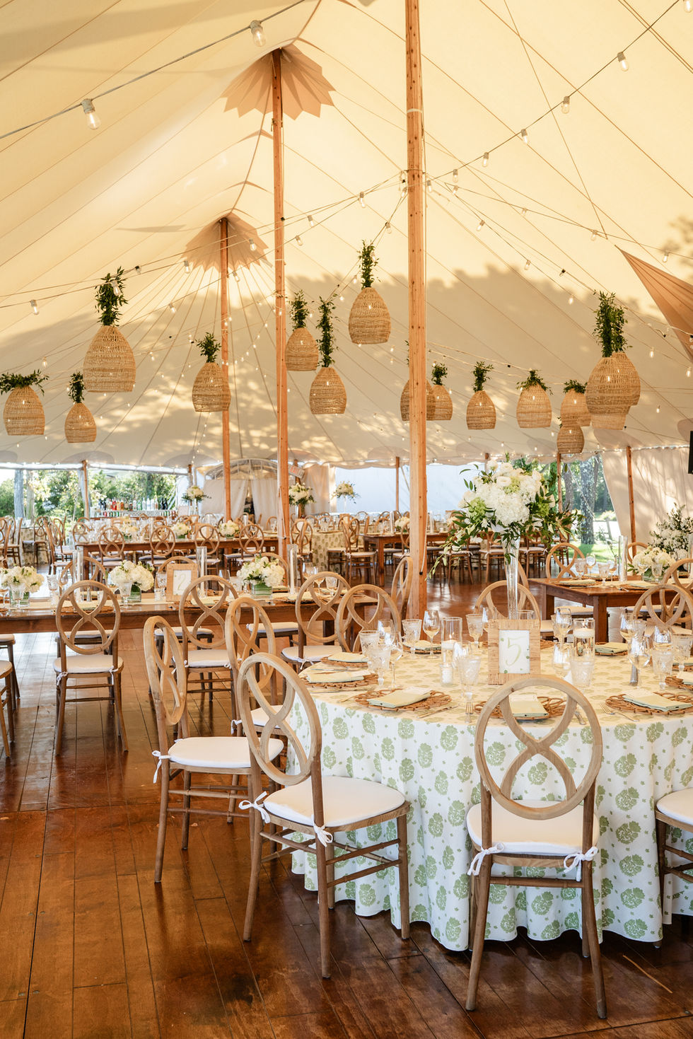 Elegant event tent with floral decorations and wooden chairs.