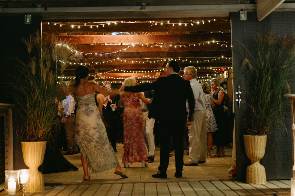 People dancing under string lights at an indoor event.
