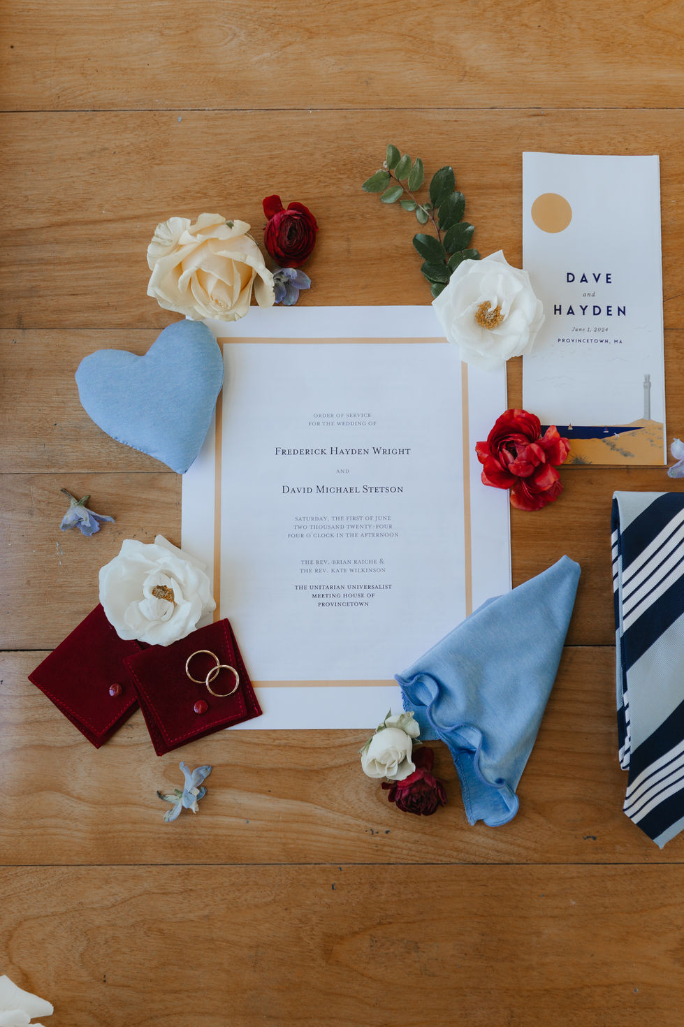 Wedding invitation with flowers and rings on table.