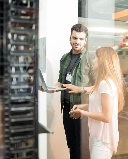 two-business-people-standing-server-room-with-laptop-discussing