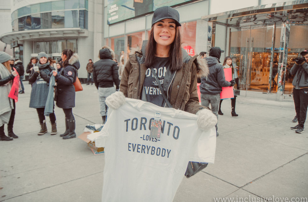 a woman is holding a white t-shirt that says toronto loves everybody