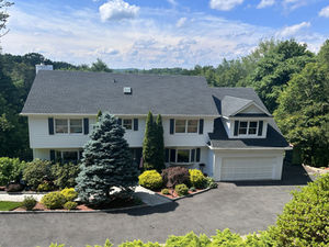 Exterior painting project in Pleasantville NY – dramatic color change transformation of a two-story house with new dark siding and white trim, boosting curb appeal.