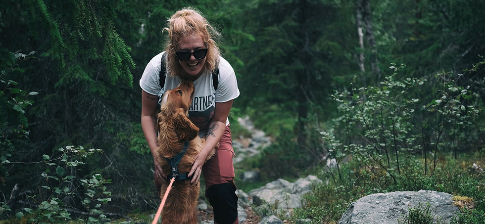 Happy woman hiking with her dog outdoors