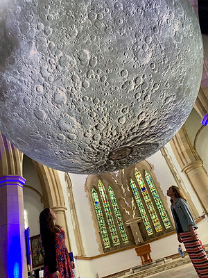 Kathryn and Hannah stand underneath the museum of the moon - a massive sphere with the moon's craters on it