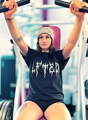 woman doing chest press in a gym wearing a lfted fitness black hardcore t-shirt and a grey beanie