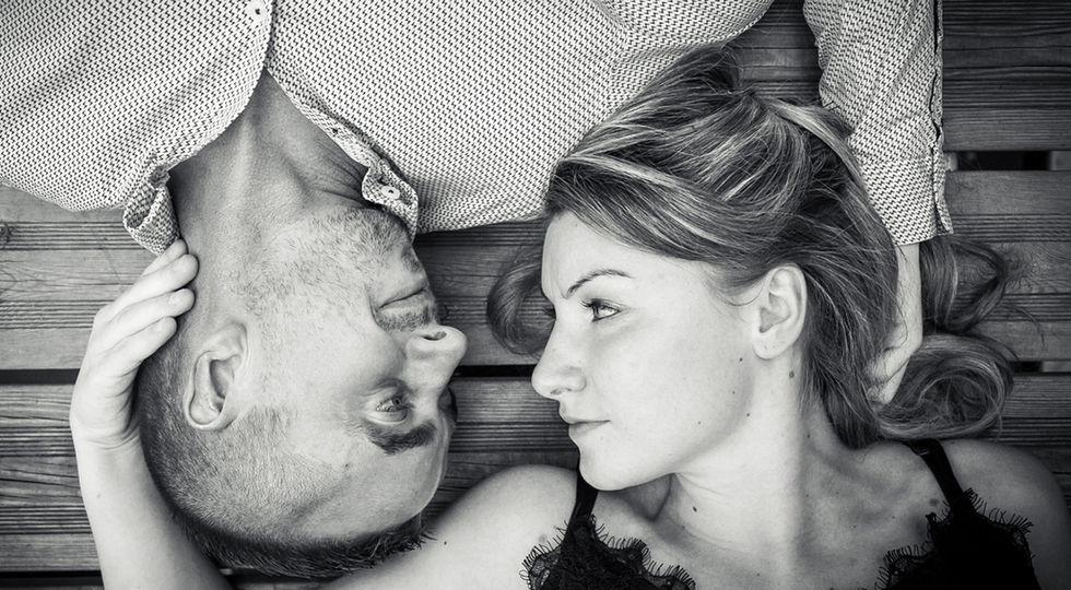 Couple allongé, têtes face à face, regard tendre, noir et blanc.