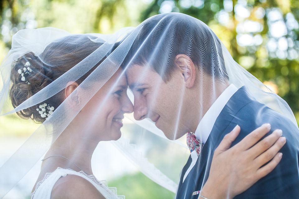 Les mariés se regardent sous le voile de la mariée.