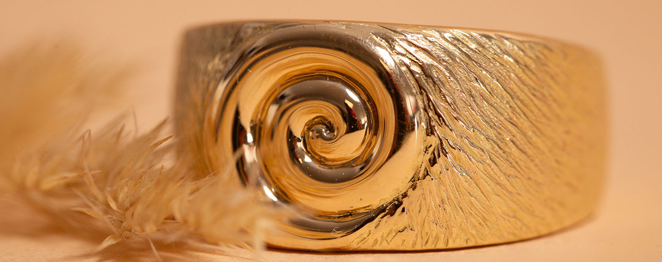 Bague en or avec spirale, surface texturée, et plume douce.