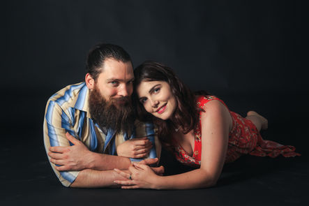 Couple souriant allongé, femme s'appuyant sur l'homme barbu.