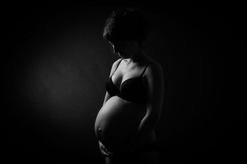 Femme enceinte en soutien-gorge noir regardant son ventre avec tendresse.