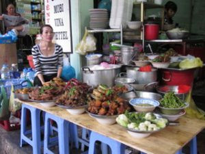 Woman selling cooked food at a market in Vietnam