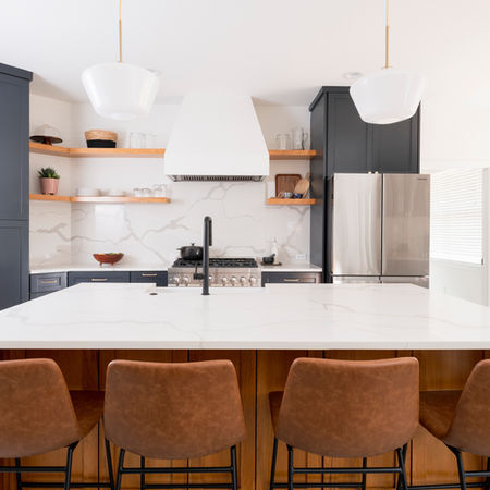 This modern-transitional kitchen remodel in Dallas, Texas features custom navy cabinetry, floating white oak shelves, a mitered quartz island and matching quartz backsplash were all delivered through our signature guided process and backed by our Ownership Promise.