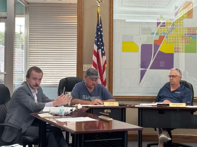 Commissioner Spencer Shipley, left, speaks while Jay Bell and Mayor Shane look on.