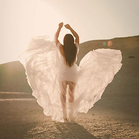 Femme en robe blanche dans la lumière, symbole de transformation profonde et d’épanouissement retrouvés grâce au Pack Renaissance.