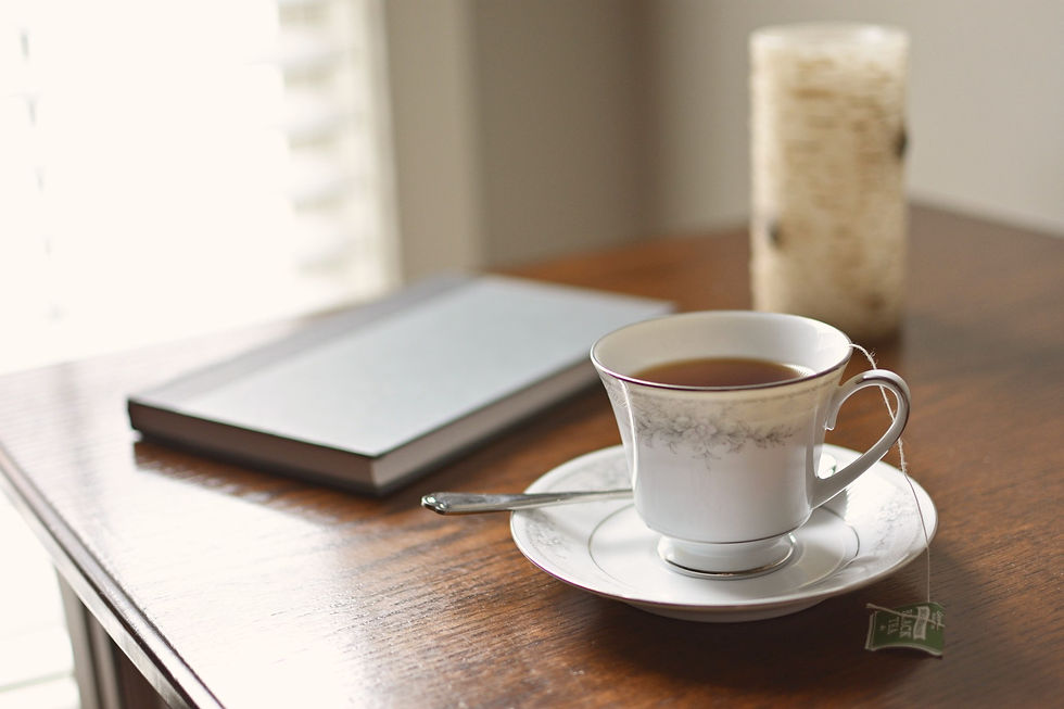 Tasse de thé, carnet ouvert et bougie sur une table en bois