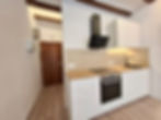 Cocina moderna, gabinetes blancos, encimera madera y pasillo.